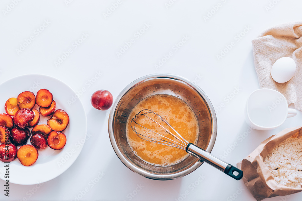 Metal bowl of whipped eggs with whisk next to bag of flour Metal bowl of whipped eggs with whisk next to bag of flour