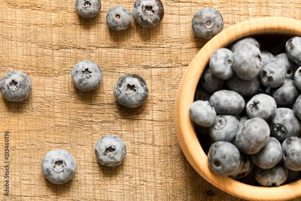 Fresh blueberries in a wooden plate. On an old wooden table. The concept of natural food . Top view. Selective focus Fresh blueberries in a wooden plate. On an old wooden table. The concept of natural food . Top view. Selective focus
