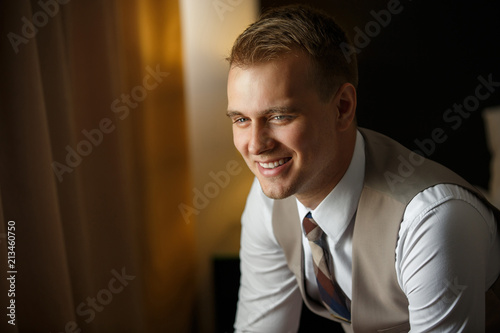 Smiling attractive man in fashionable tuxedo, waiting for successful business day. Happy man portrait. Indoors.