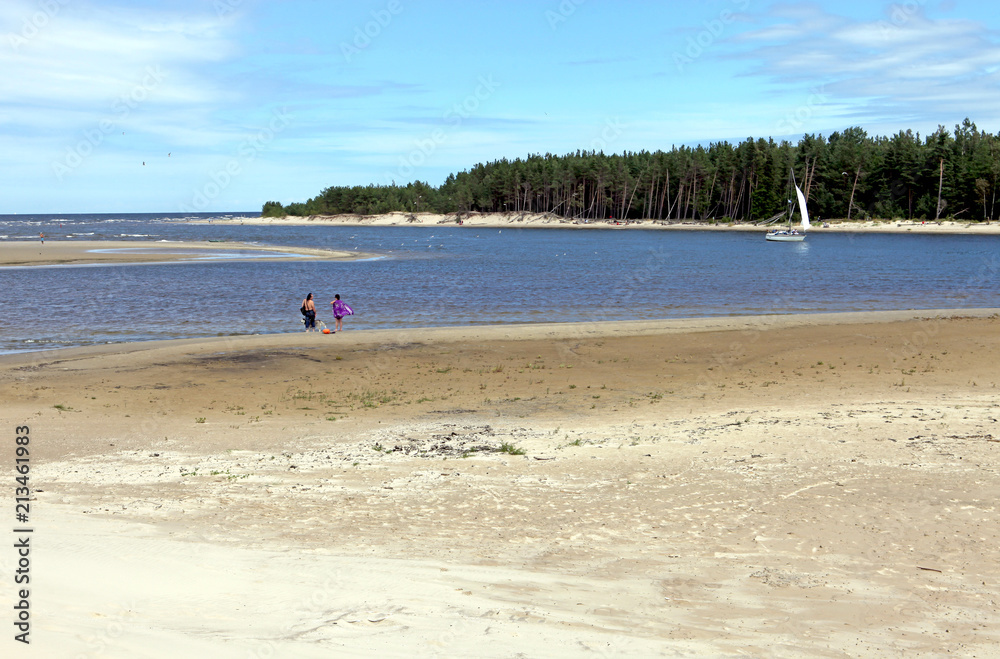 People walking on a beautiful sandy beach with dunes, lagoon and forest, Baltic Sea Jurmala, Latvia