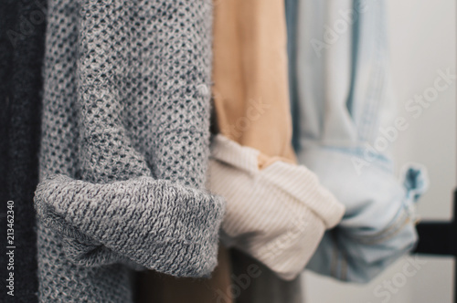 Close up of woolen cardigan, linen and denim jackets rolled up sleeves. Cozy and minimal lifestyle, capsule wardrobe. Selective focus, horizontal