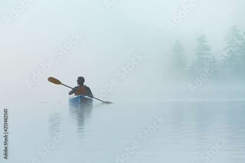 Senior Solo Traveling Man Kayaking in Dense Fog in Wilderness Waters