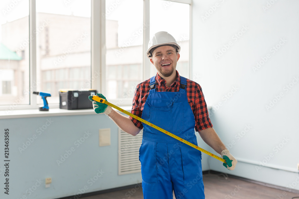 Happy white male builder infront of window with tape measure Happy white male builder infront of window with tape measure