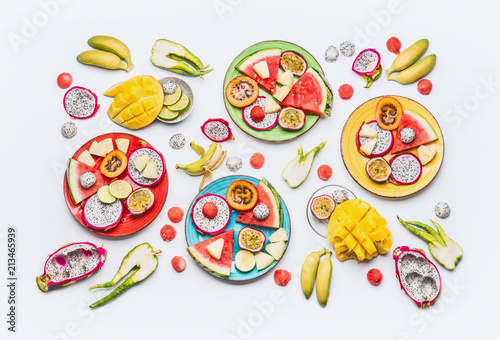 Flat lay of summer various colorful sliced tropical fruits and berries plates and bowls on white background with ingredients, top view. Clean and healthy lifestyle background