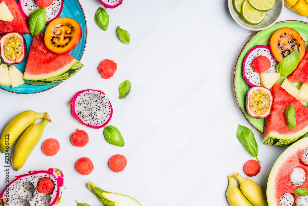Summer clean and healthy lifestyle  background with various colorful sliced tropical fruits and berries plates and bowls on white  background, top view, frame