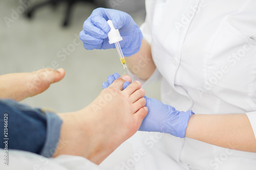 Fotografie A healthy foot, beautician applies a care product