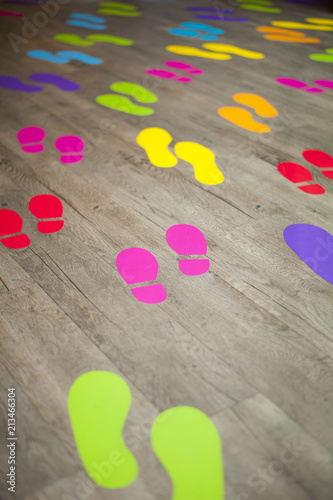 Shot of many colorful footsteps on a wooden floor that are crowding together