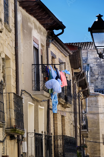 Detail of an iron balcony with clothes hanging to dry in a stone house typical of the villages of northern Spain © peizais