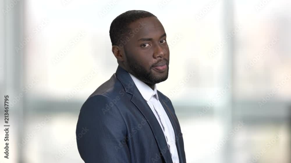 Playful black man in business suit. Bright blurred windows background. Playful black man in business suit. Bright blurred windows background.