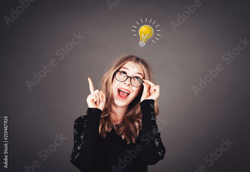 Junge intelligente Frau mit Brille hat eine Idee, Glühbirne photo