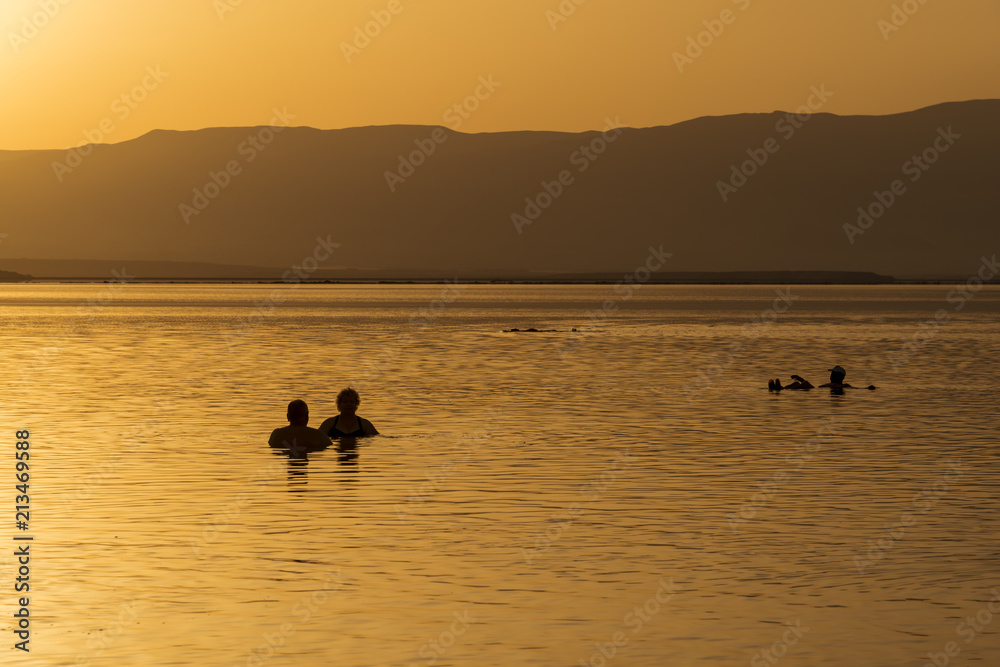 People bathing in the dead sea at sunrise