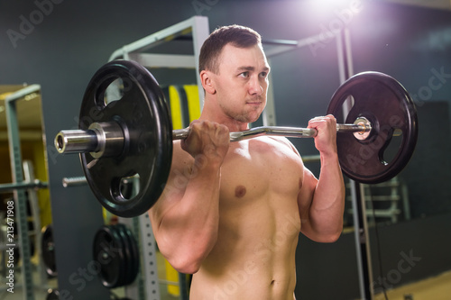 Muscular young man lifting weights in gym