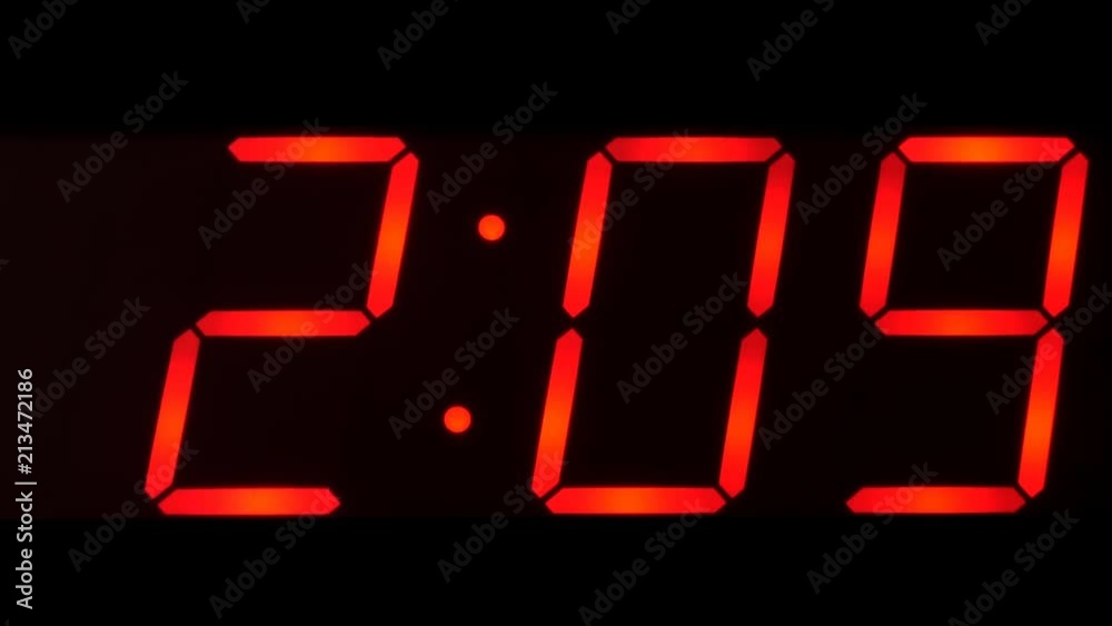 Close up of huge black,dark clock digital display,screen showing time between 2:00 AM or PM and 2:59 and beyond in big red digits