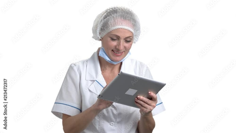Portrait of confident female doctor using digital tablet. Woman in medical uniform chatting with someone using tablet. White isolated background. Portrait of confident female doctor using digital tablet. Woman in medical uniform chatting with someone using tablet. White isolated background.
