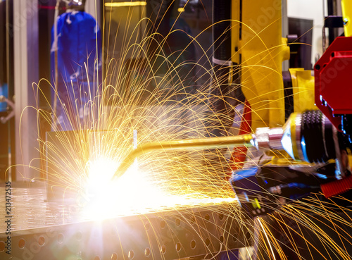 industrial yellow robot welder close - up conduct welding of metal parts, metal droplets are beautifully sprinkled in all directions photo