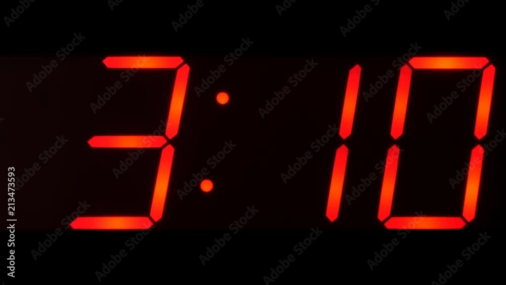 Close up of huge black,dark clock digital display,screen showing time between 3:00 AM or PM and 3:59 and beyond in big red digits