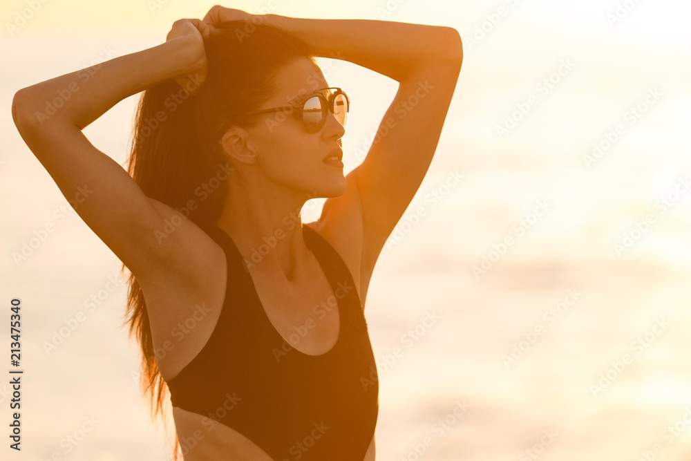 pretty young teen with long hair tanning in black bikini against an ocean and sunset . concept of happy holiday and resort time. pretty young teen with long hair tanning in black bikini against an ocean and sunset . concept of happy holiday and resort time.