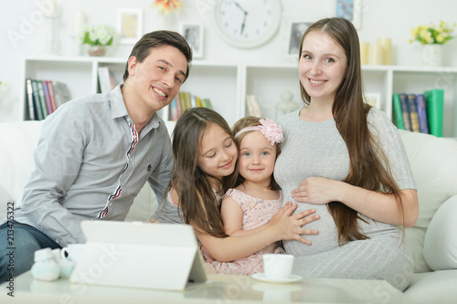 happy pregnant woman with husband and daughters