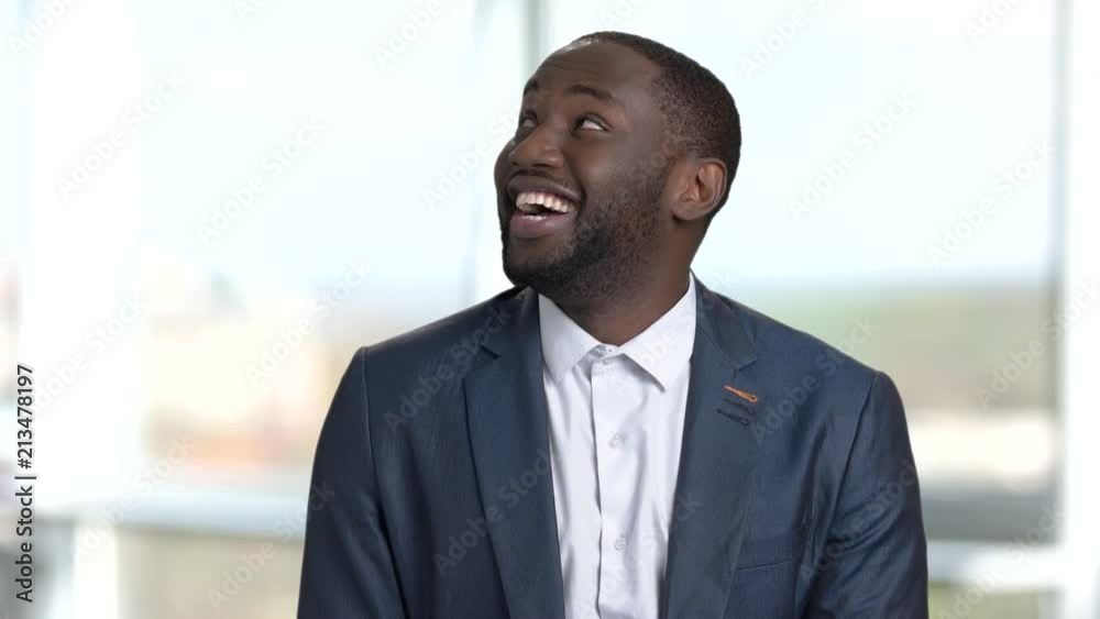 Happy cheerful african man looking around. Blurred windows background. Happy cheerful african man looking around. Blurred windows background.