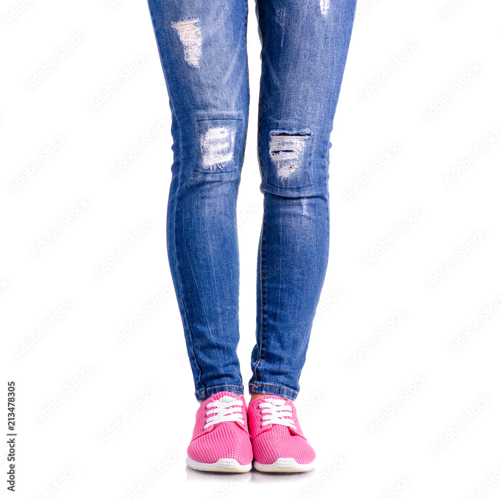 Woman's legs blue denim pink sneakers on white background isolation Woman's legs blue denim pink sneakers on white background isolation