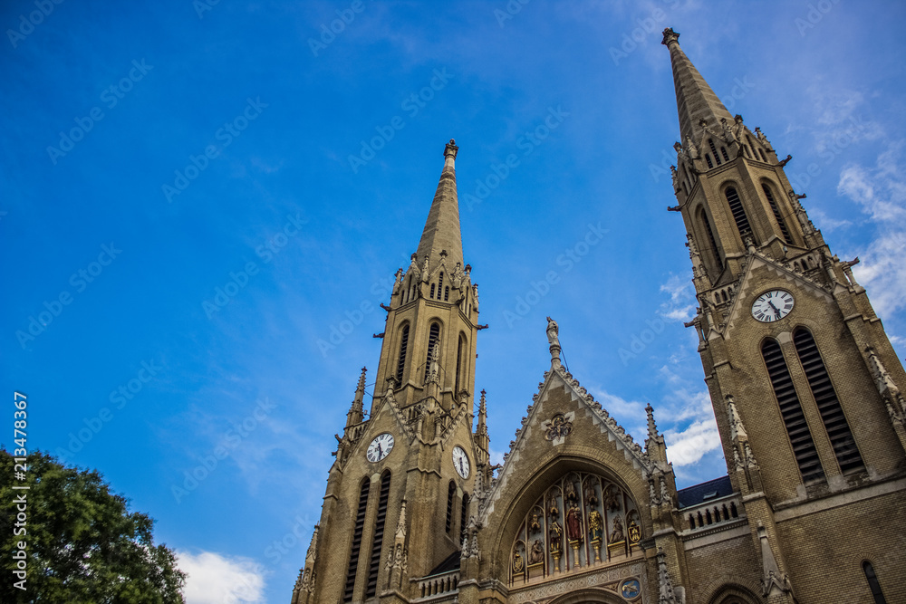 old medieval gothic church facade from below on blue sky background in bright summer day time