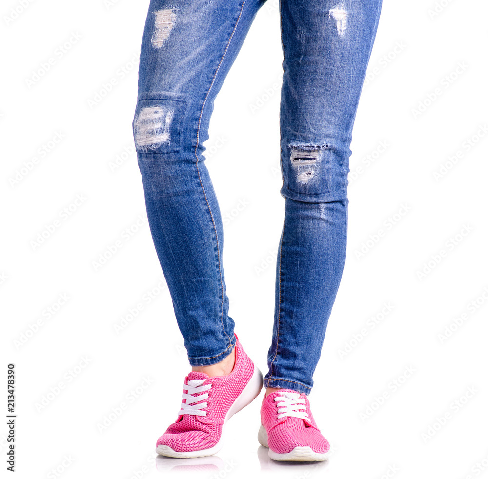 Woman's legs blue denim pink sneakers on white background isolation Woman's legs blue denim pink sneakers on white background isolation