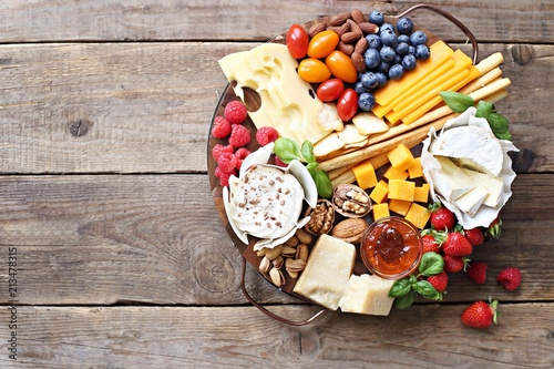 Cheese platter with fresh berries and nuts on a rustic wooden table. Overhead view.
