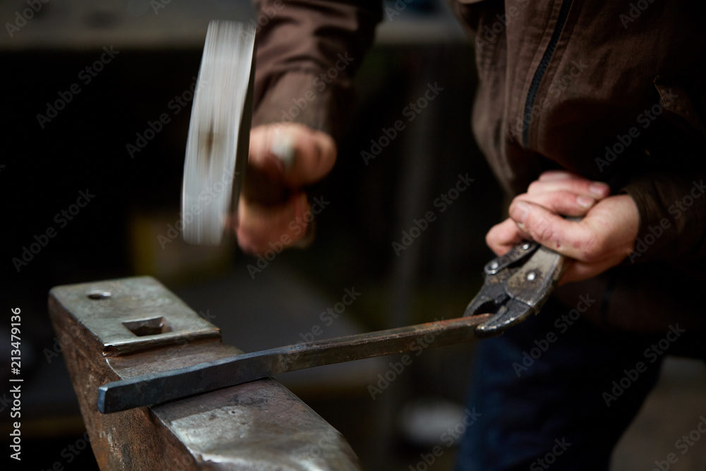 Close-up of a blacksmith's hands manipulating a metal piece above his forge, selective focus. Close-up of a blacksmith's hands manipulating a metal piece above his forge, selective focus.