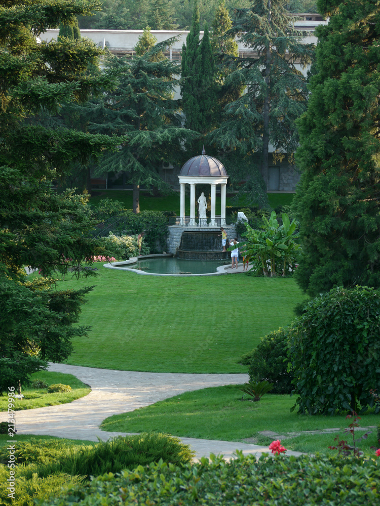 Obraz premium Monument statue under the dome near the lake in a green, clean park
