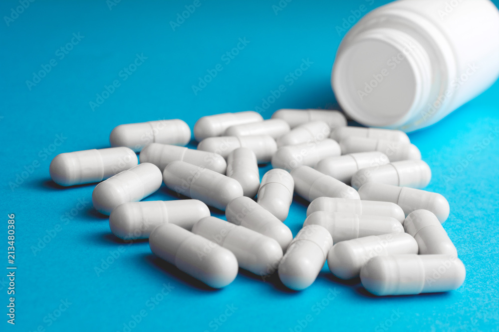 Heap of pills or tablets capsule plastic drugs bottle blue background. Drug prescription for treatment, Medicine pills Pharmaceutical medicament antibiotic, Pharmacy drugstore concept.