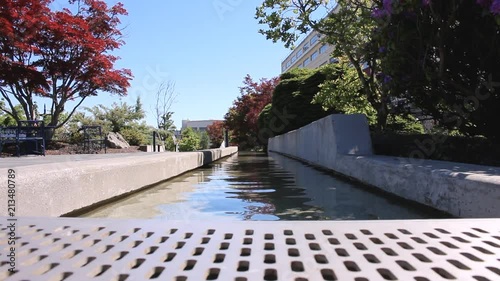 Urban water park with slow moving water trees and blue sky shot in summer or spring 1920 x 1080 24 frp photo