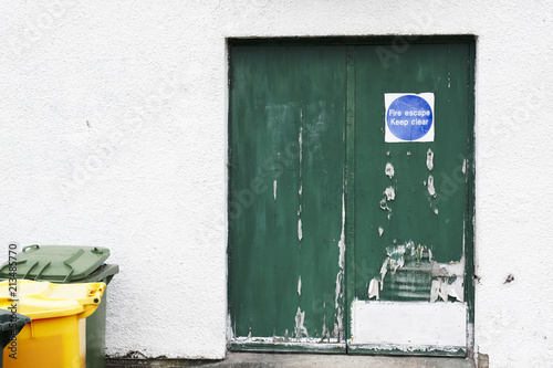 Fire exit keep clear sign on building evacuation door green on white wall background