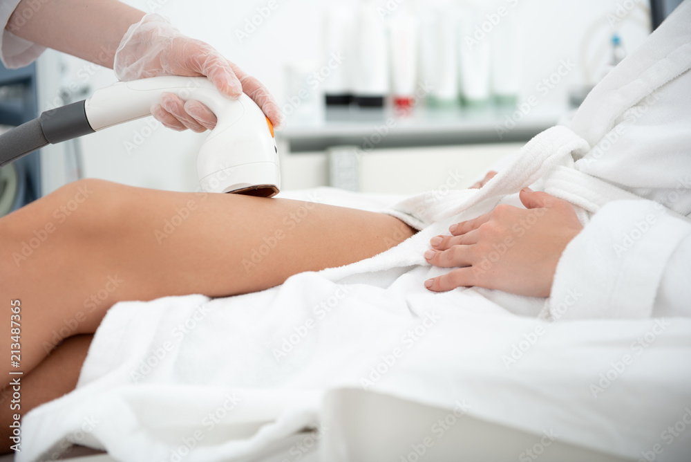 Close up girl hand in glove making hair removal with special digital device in clinic