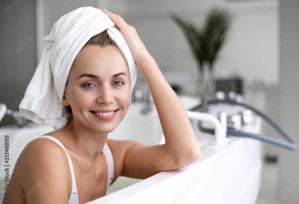 Portrait of beaming lady holding towel by hand while swimming in bath during procedure
