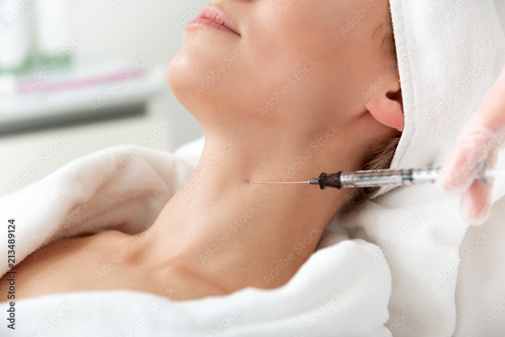 Fototapeta premium Optimistic female during treatment procedure. Cosmetologist hands in gloves introducing medication