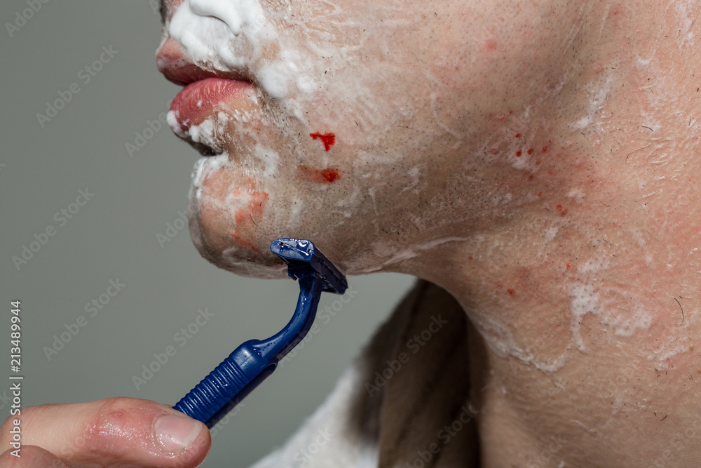 Fototapeta premium Disposable razor. Man is shaving. Shaving by yourself painful and unpleasant. Inconvenience of home shaving. Trust to a professional hairdresser. Caring for yourself and body. Cosmetics for men