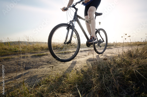 Fototapeta Naklejka Na Ścianę i Meble -  Male cyclist driving by rural dirt road outdoors. Low angle view
