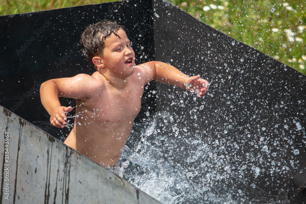 Fototapeta premium A boy is swimming in the pool with a spray