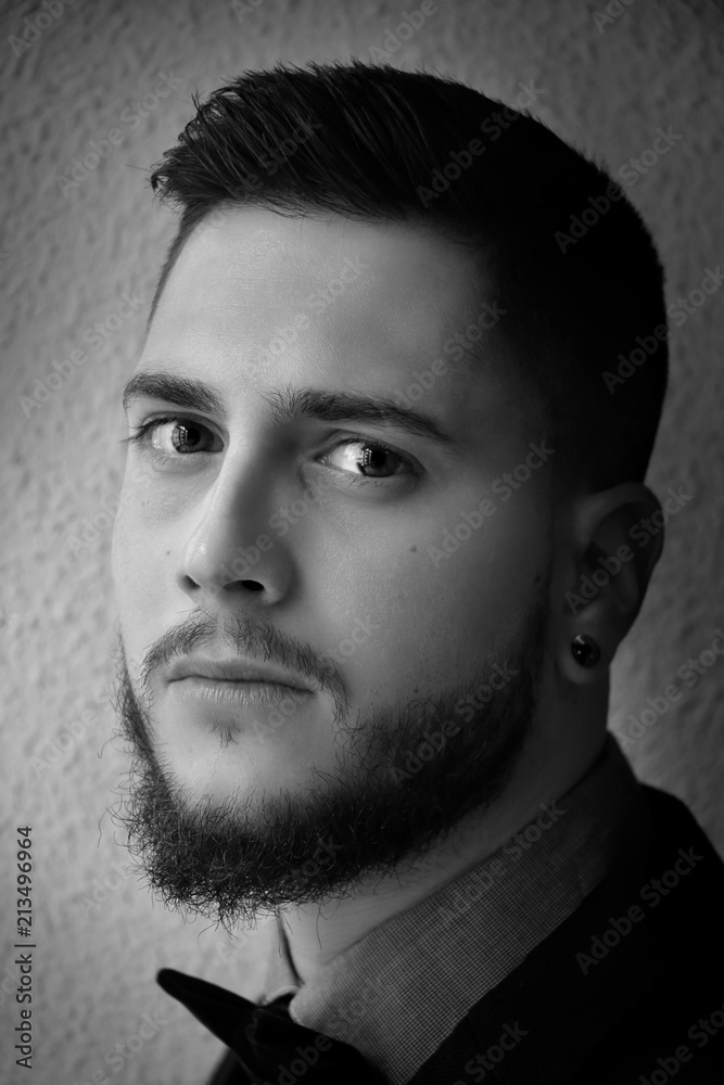 Obraz premium Black and white portrait of a handsome boy with a beard dressed smartly