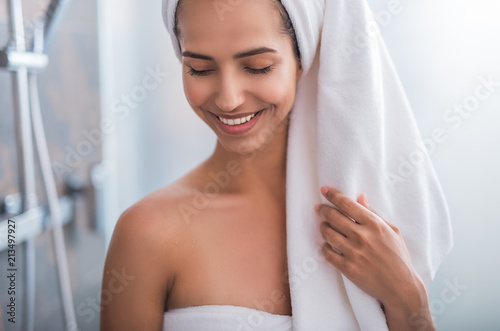 Outgoing girl wrapping in cozy towel with closing eyes after taking bath. She gesticulating hand