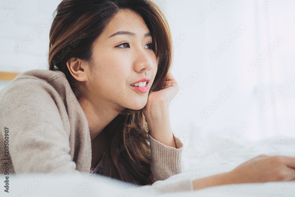Portrait beautiful young Asian woman on bed at home in the morning. Cheerful Asian woman wearing a comfortable sweater and smiling on her bed. Relaxing room. lifestyle asia woman at home concept. Portrait beautiful young Asian woman on bed at home in the morning. Cheerful Asian woman wearing a comfortable sweater and smiling on her bed. Relaxing room. lifestyle asia woman at home concept.