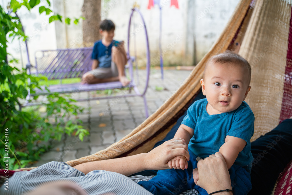 The little boy and mother are sitting at the hammock, both are happy The little boy and mother are sitting at the hammock, both are happy