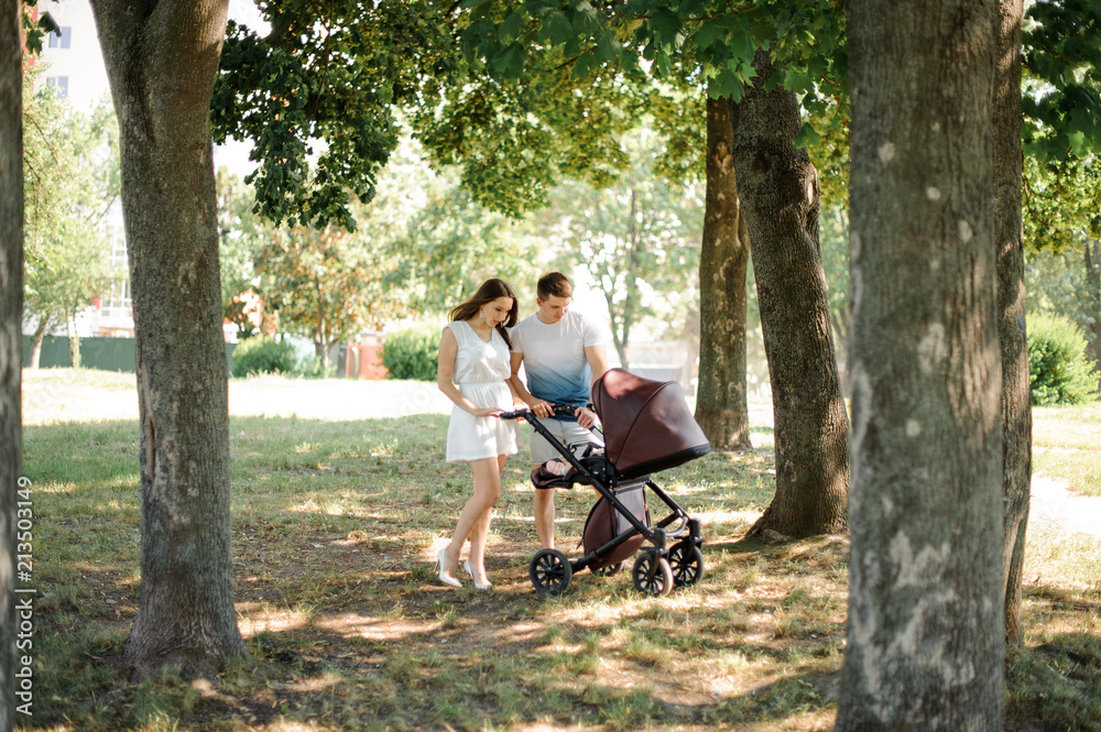 Happy parents and their little daughter in the babby carriage Happy parents and their little daughter in the babby carriage