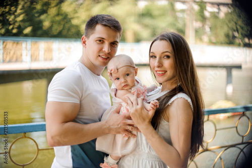 Parents holding their little cute daughter in the public park © fesenko