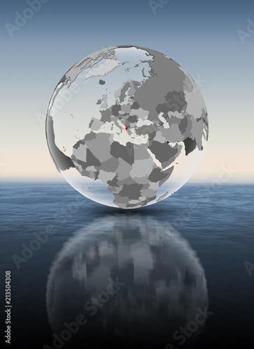 Albania on translucent globe above water