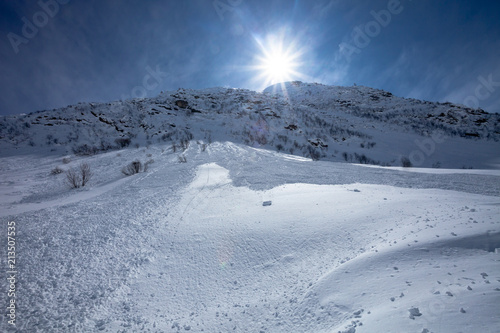 Suin lights fall on a snowed downhill after avalanche.