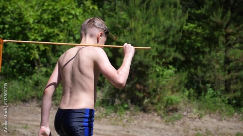 The guy after fishing is on a forest road. In the hands of holds net. Hot summer day. Summer vacation in the village. photo