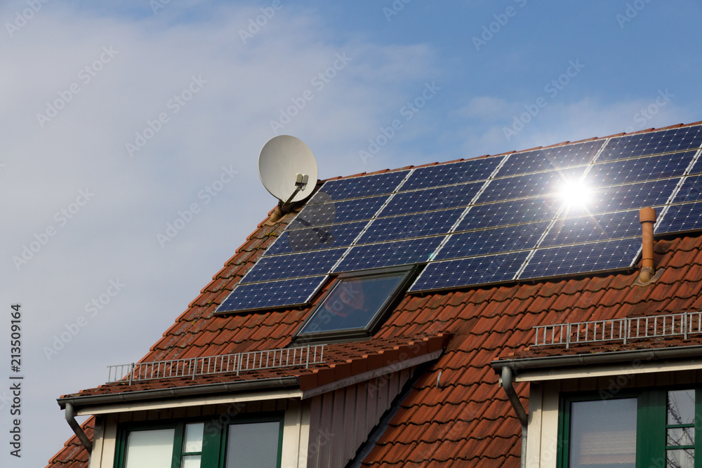 Fototapeta premium Solar panels on a red roof reflecting the sun