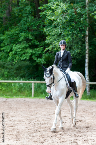 Teenage girl equestrian in dress uniform riding horseback on arena © AnnaElizabeth