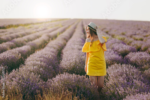 Fototapeta Naklejka Na Ścianę i Meble -  Portrait of young sensual beautiful woman in yellow dress, hat on purple lavender flower blossom meadow field outdoors on summer nature background. Tender female near flowering bush. Lifestyle concept